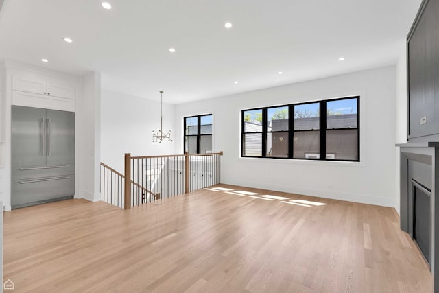 3905 N Drake Ave, Chicago, IL 60618 - unfurnished living room with a chandelier, light wood-type flooring, recessed lighting, and baseboards