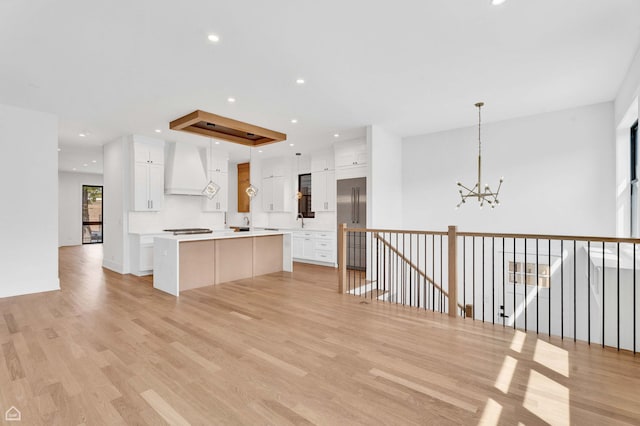 3905 N Drake Ave, Chicago, IL 60618 - kitchen featuring premium range hood, a chandelier, a kitchen island, light wood-type flooring, and white cabinets