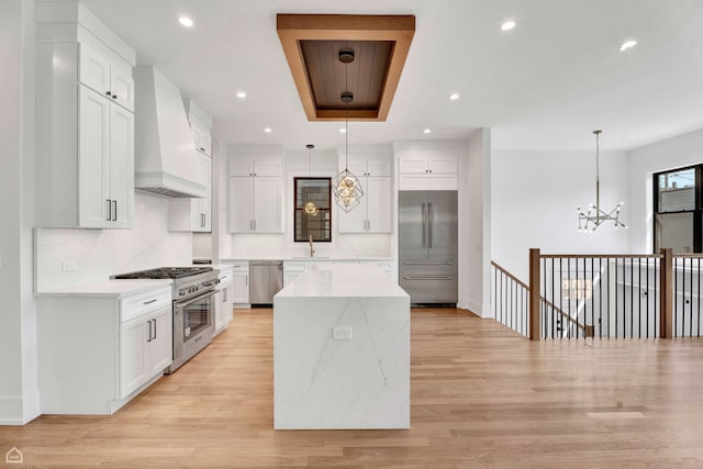 3905 N Drake Ave, Chicago, IL 60618 - kitchen featuring premium range hood, high end appliances, a chandelier, a kitchen island, and white cabinetry