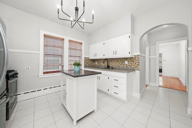 5331 W Schubert Ave, Chicago, IL 60639 - kitchen with arched walkways, light tile patterned flooring, white cabinetry, and a kitchen island