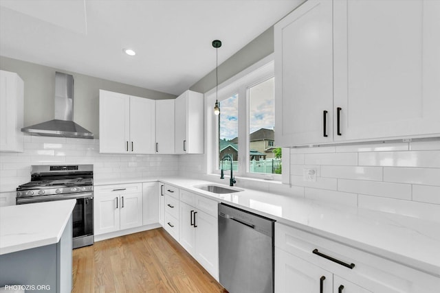 7218 S 78th Ave, Bridgeview, IL 60455 - kitchen featuring wall chimney range hood, appliances with stainless steel finishes, a sink, light stone counters, and light wood-type flooring