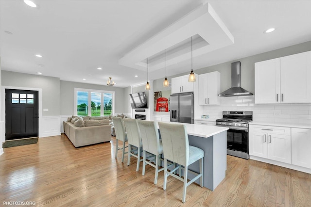 7218 S 78th Ave, Bridgeview, IL 60455 - kitchen with wall chimney range hood, appliances with stainless steel finishes, a kitchen bar, white cabinetry, and wainscoting