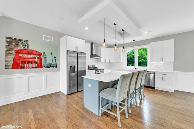7218 S 78th Ave, Bridgeview, IL 60455 - kitchen featuring stainless steel appliances, wall chimney exhaust hood, a breakfast bar, a kitchen island, and white cabinetry
