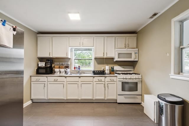 1818 W 9th St, Dixon, IL 61021 - kitchen featuring white appliances, crown molding, light countertops, a sink, and baseboards