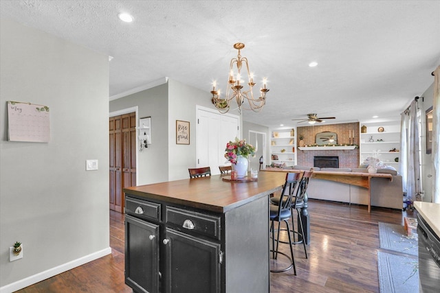 1517 Bridge Point Ln, Champaign, IL 61822 - kitchen with dark cabinets, a fireplace, a kitchen bar, a ceiling fan, and dark wood-type flooring