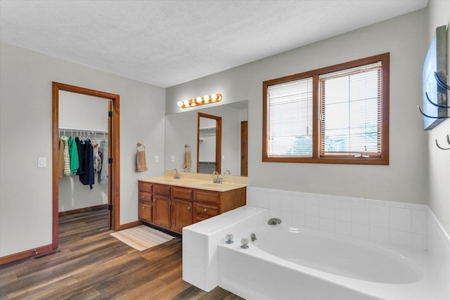 1517 Bridge Point Ln, Champaign, IL 61822 - bathroom featuring a garden tub, double vanity, wood finished floors, a spacious closet, and a textured ceiling