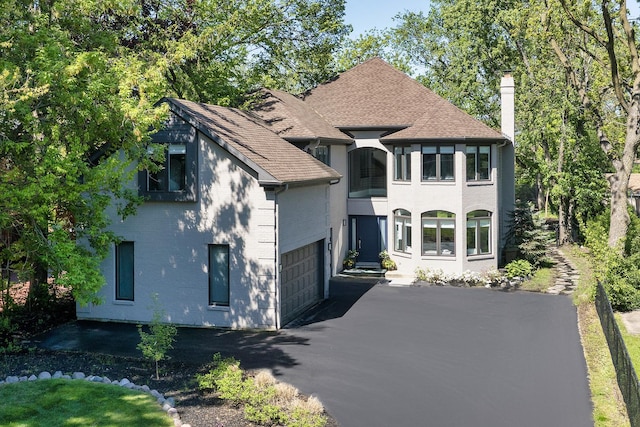 244 Kenmore Ave, Deerfield, IL 60015 - french country style house with asphalt driveway, a chimney, an attached garage, brick siding, and roof with shingles