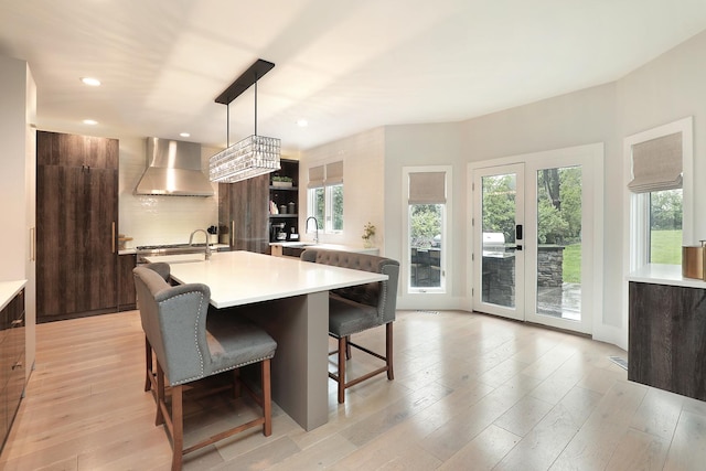 244 Kenmore Ave, Deerfield, IL 60015 - kitchen with wall chimney range hood, modern cabinets, open shelves, light countertops, and a kitchen island with sink