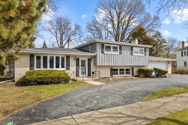 410 W Kirchhoff Rd, Arlington Heights, IL 60005 - tri-level home with a chimney, board and batten siding, brick siding, a garage, and a front lawn
