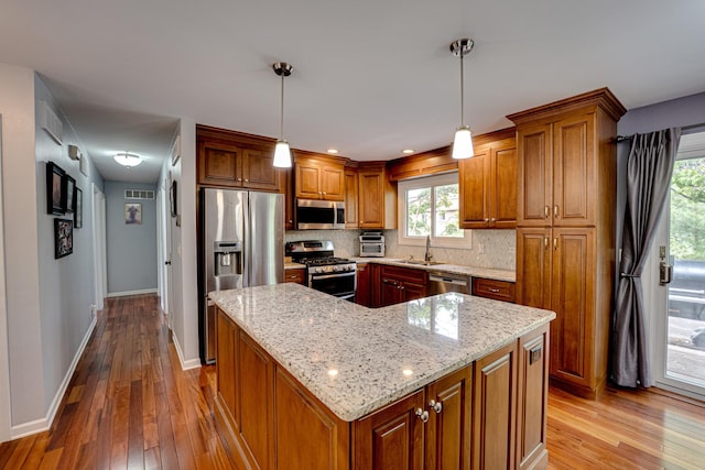 24W474 Surf Ct, Naperville, IL 60540 - kitchen featuring appliances with stainless steel finishes, a sink, wood-type flooring, brown cabinets, and decorative backsplash