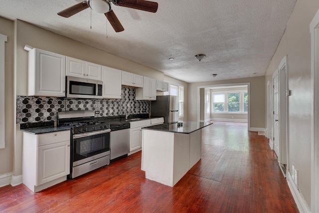 1837 S 50th Ct, Cicero, IL 60804 - kitchen with appliances with stainless steel finishes, a textured ceiling, decorative backsplash, white cabinetry, and dark wood finished floors