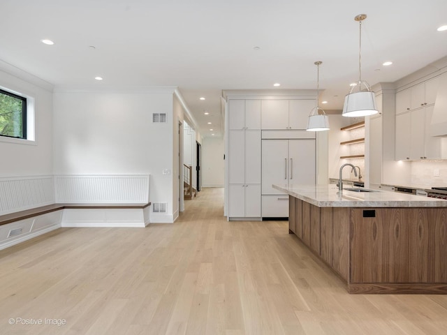 1853 W Barry Ave, Chicago, IL 60657 - kitchen featuring modern cabinets, a sink, white cabinets, light wood-style flooring, and light stone counters