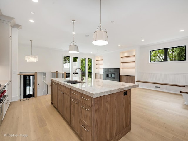 1853 W Barry Ave, Chicago, IL 60657 - kitchen featuring a sink, light wood-style floors, an island with sink, brown cabinetry, and wainscoting