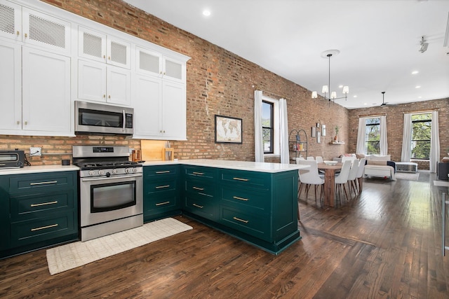 1014 N Milwaukee Ave Unit 2, Chicago, IL 60642 - kitchen featuring stainless steel appliances, green cabinetry, brick wall, white cabinets, and dark wood finished floors