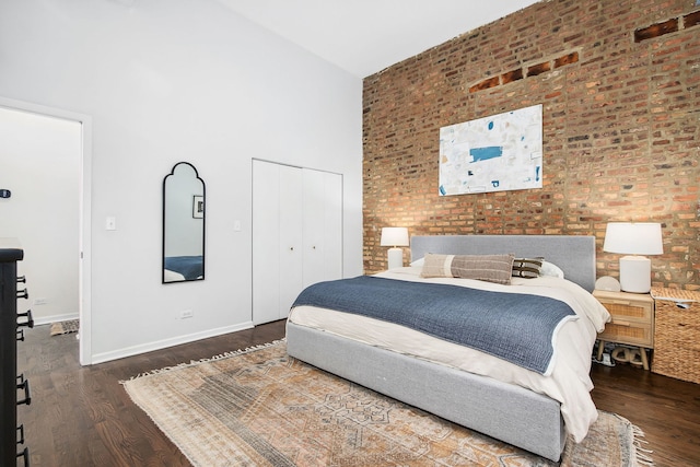 1014 N Milwaukee Ave Unit 2, Chicago, IL 60642 - bedroom with a towering ceiling, wood finished floors, a closet, baseboards, and brick wall