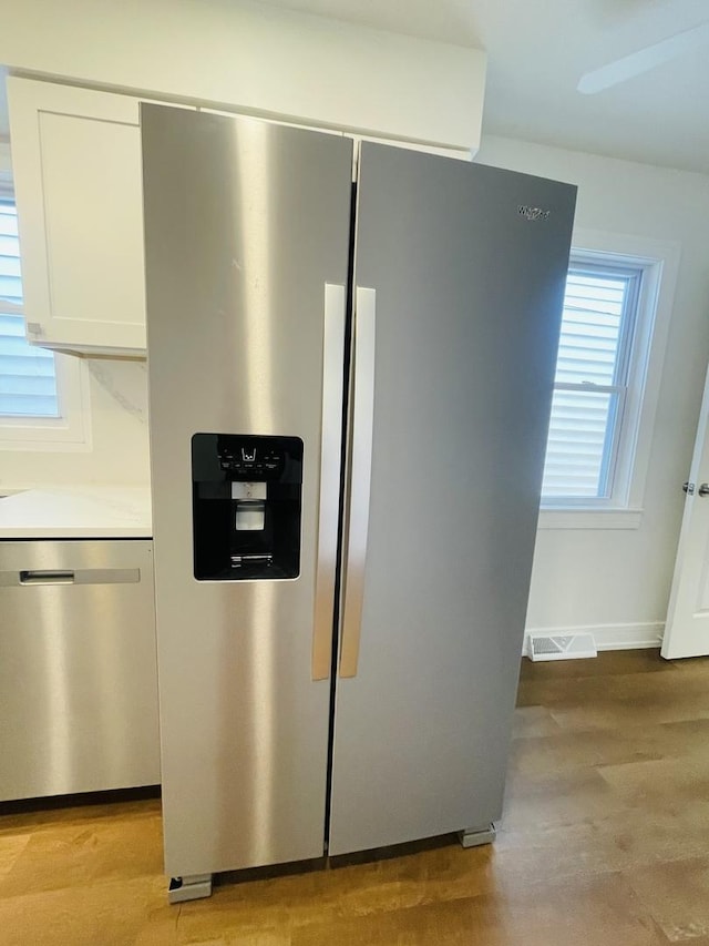 4634 N Hamlin Ave, Chicago, IL 60625 - detailed view of appliances with stainless steel finishes, white cabinetry, light wood-style floors, and light countertops