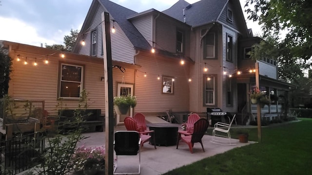 403 E Hickory St, Fairbury, IL 61739 - rear view of house featuring a patio, a lawn, a shingled roof, and a fire pit