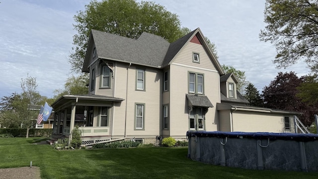 403 E Hickory St, Fairbury, IL 61739 - victorian home featuring a covered pool, a front lawn, a sunroom, and roof with shingles