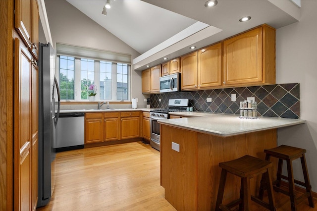 1508 Parkside Dr, Plainfield, IL 60586 - kitchen with stainless steel appliances, a peninsula, light wood-style flooring, decorative backsplash, and light countertops