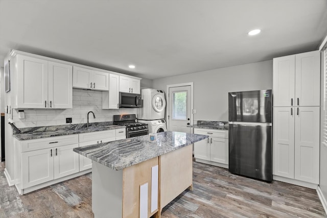 1011 Cypress Ln, Joliet, IL 60435 - kitchen with stainless steel appliances, stacked washer and clothes dryer, stone counters, wood finished floors, and a kitchen island