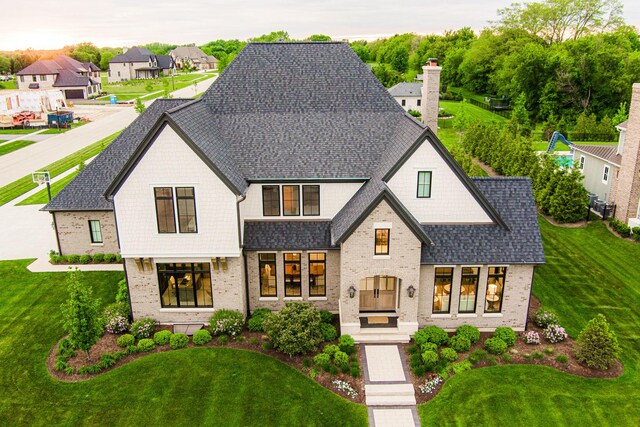 5N257 Switchgrass Ln, Saint Charles, IL 60175 - french country home featuring roof with shingles, brick siding, a front yard, and a residential view