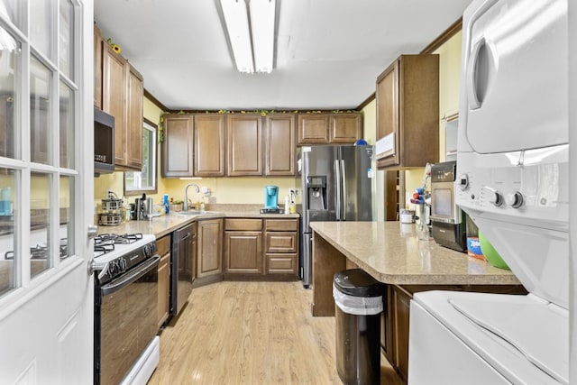 8 Sparrow Rd, Carpentersville, IL 60110 - kitchen featuring stacked washing machine and dryer, stainless steel appliances, light wood-type flooring, a sink, and light countertops