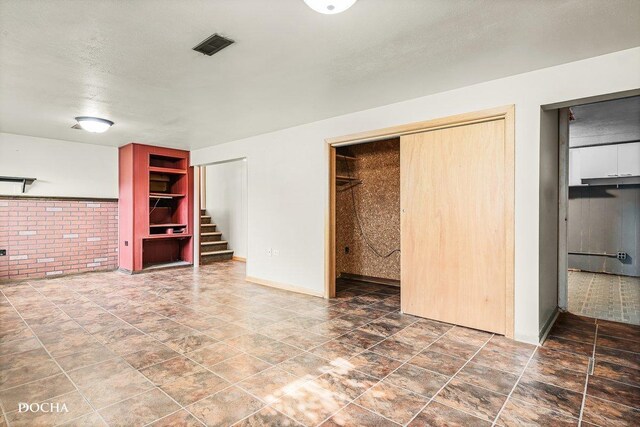 9446 Magnolia Ave, Mokena, IL 60448 - unfurnished living room featuring stairs and brick wall
