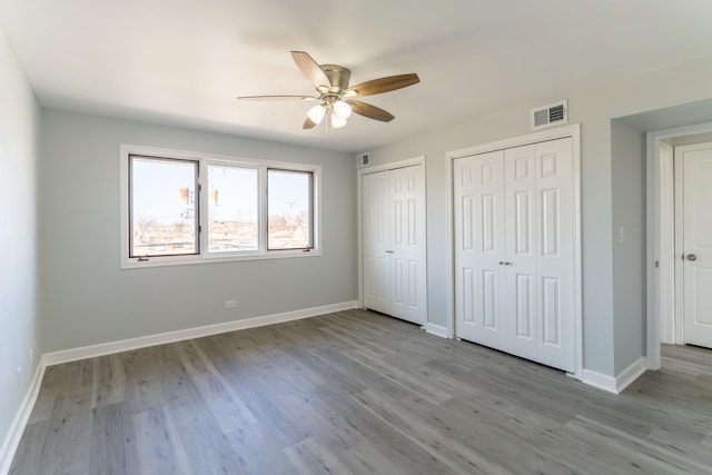6154 W 63rd St Unit 3W, Chicago, IL 60638 - unfurnished bedroom featuring two closets, wood finished floors, baseboards, and a ceiling fan