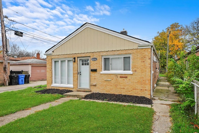 10244 S Crandon Ave, Chicago, IL 60617 - view of front of property featuring brick siding, a chimney, a front yard, and an outdoor structure