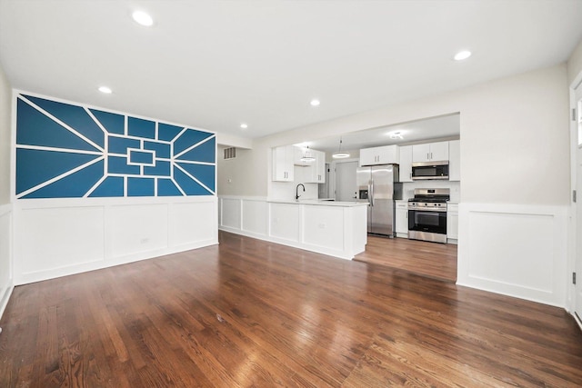 10244 S Crandon Ave, Chicago, IL 60617 - unfurnished living room with a decorative wall, wainscoting, dark wood finished floors, recessed lighting, and a sink
