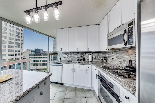 1580 Sherman Ave Unit 1006, Evanston, IL 60201 - kitchen featuring appliances with stainless steel finishes, a sink, backsplash, light tile patterned floors, and white cabinetry