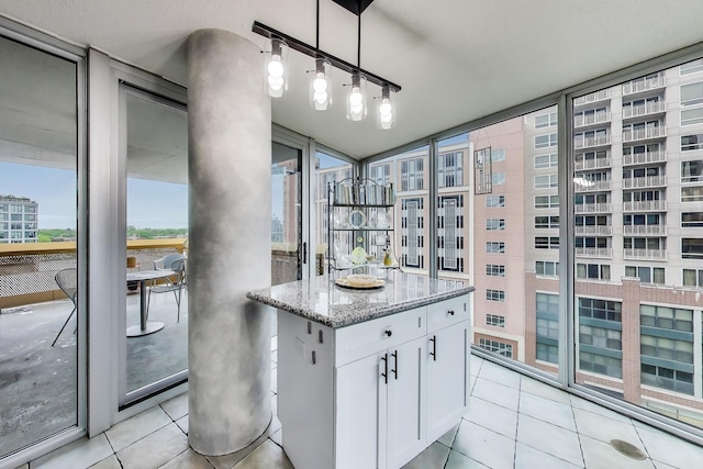 1580 Sherman Ave Unit 1006, Evanston, IL 60201 - kitchen with white cabinetry, light stone counters, light tile patterned floors, a city view, and a kitchen island