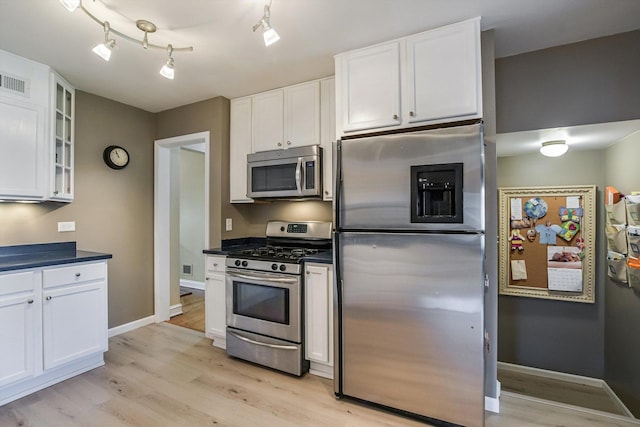 1212 S Greenwood Ave, Park Ridge, IL 60068 - kitchen with stainless steel appliances, white cabinetry, light wood-style flooring, dark countertops, and glass insert cabinets