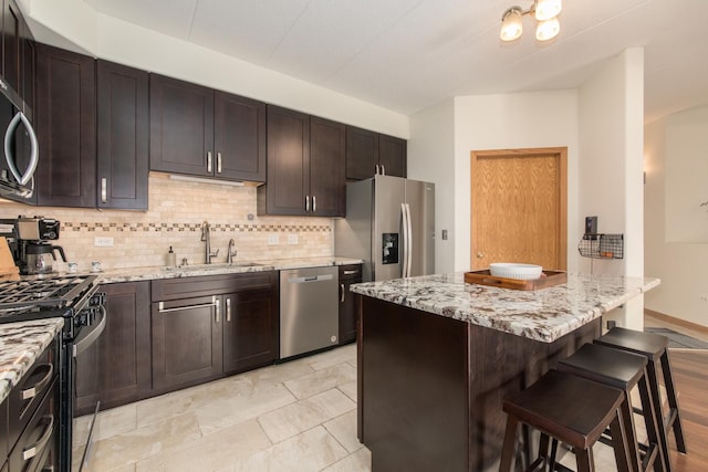 1705 Pavilion Way Unit 401, Park Ridge, IL 60068 - kitchen featuring stainless steel appliances, a sink, decorative backsplash, a breakfast bar area, and light stone countertops