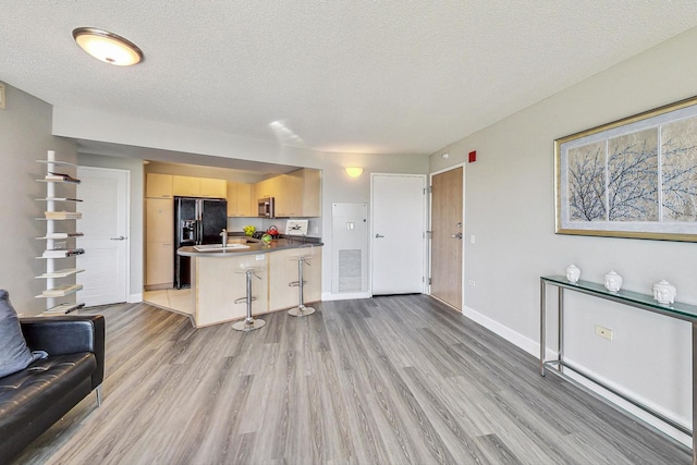 1720 Maple Ave Unit 1270, Evanston, IL 60201 - kitchen featuring open floor plan, light brown cabinets, light wood-type flooring, black refrigerator with ice dispenser, and a peninsula