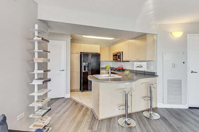 1720 Maple Ave Unit 1270, Evanston, IL 60201 - kitchen with black refrigerator with ice dispenser, stainless steel microwave, a peninsula, light wood-style flooring, and a sink
