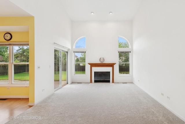 17083 W Tiger Tail Ct, Gurnee, IL 60031 - unfurnished living room featuring carpet, a towering ceiling, a fireplace with flush hearth, and baseboards