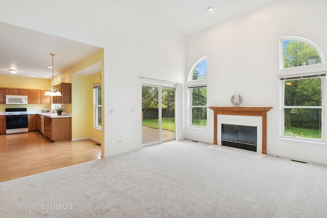17083 W Tiger Tail Ct, Gurnee, IL 60031 - unfurnished living room with light carpet, plenty of natural light, a tile fireplace, a high ceiling, and a chandelier