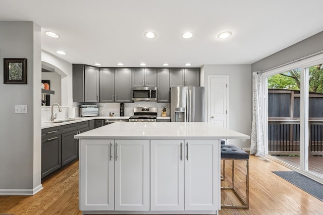 6173 Dixon Dr, Lisle, IL 60532 - kitchen with stainless steel appliances, gray cabinets, a sink, a center island, and decorative backsplash