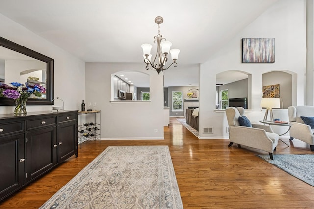 6173 Dixon Dr, Lisle, IL 60532 - dining area featuring dark wood-type flooring, arched walkways, a chandelier, and baseboards