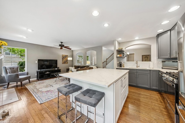 6173 Dixon Dr, Lisle, IL 60532 - kitchen with arched walkways, gray cabinets, black range with gas cooktop, a sink, and recessed lighting