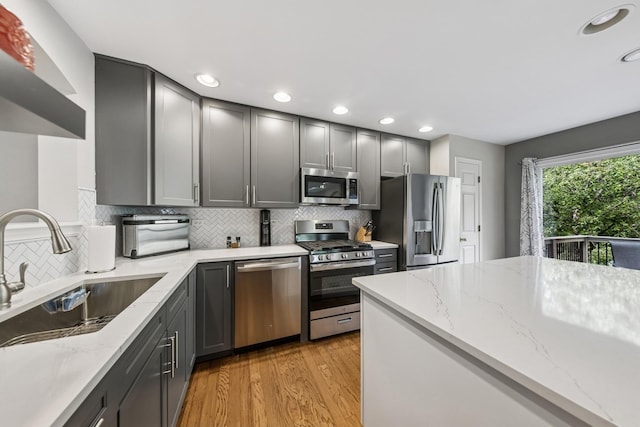 6173 Dixon Dr, Lisle, IL 60532 - kitchen with appliances with stainless steel finishes, a sink, light wood-style flooring, gray cabinetry, and decorative backsplash