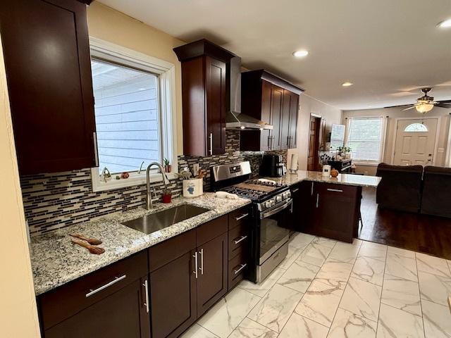 431 Edward St, Sycamore, IL 60178 - kitchen featuring gas range, a sink, wall chimney exhaust hood, a peninsula, and light stone counters