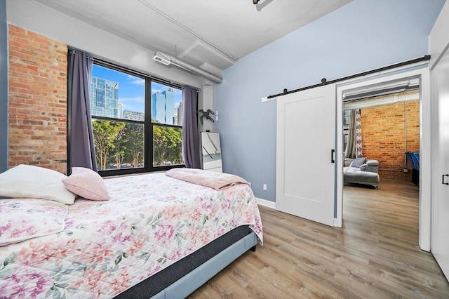 1516 S Wabash Ave Unit 306, Chicago, IL 60605 - bedroom featuring wood finished floors, a barn door, baseboards, and brick wall