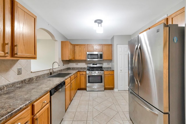 675 Fieldcrest Dr Unit 1A, South Elgin, IL 60177 - kitchen featuring appliances with stainless steel finishes, a sink, backsplash, arched walkways, and light tile patterned flooring