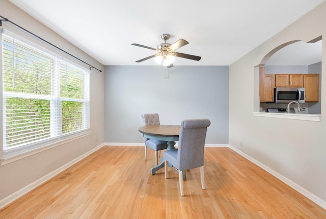 675 Fieldcrest Dr Unit 1A, South Elgin, IL 60177 - dining room featuring light wood-type flooring, baseboards, ceiling fan, and arched walkways