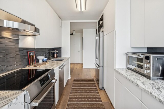 5445 N Sheridan Rd Unit 2715, Chicago, IL 60640 - kitchen with appliances with stainless steel finishes, a sink, range hood, wood finished floors, and decorative backsplash