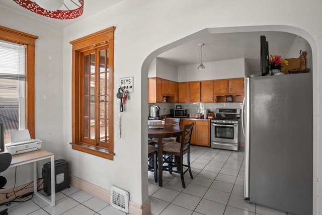 2403 Highland Ave, Berwyn, IL 60402 - kitchen featuring appliances with stainless steel finishes, arched walkways, light tile patterned floors, brown cabinets, and backsplash