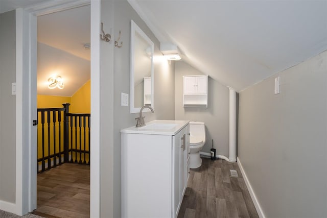 709 S Oak St, Bloomington, IL 61701 - bathroom with wood finished floors, vanity, toilet, lofted ceiling, and baseboards