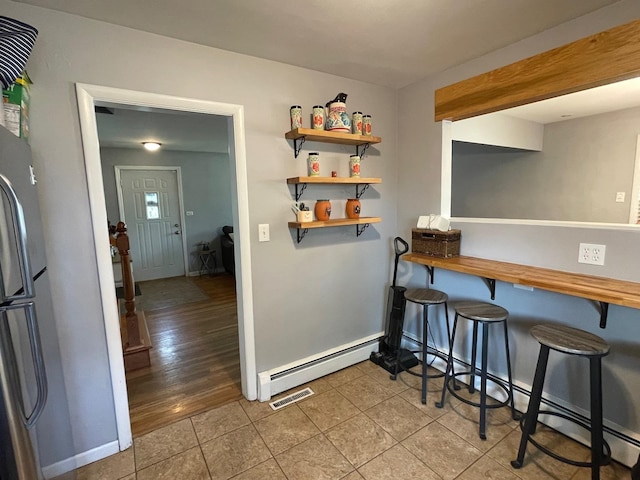 165 Kathleen Dr, Elgin, IL 60123 - kitchen featuring a baseboard heating unit, wood counters, freestanding refrigerator, a kitchen bar, and light tile patterned flooring
